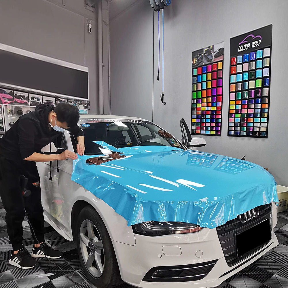 gloss sky blue car wrap being installed on a vehicle