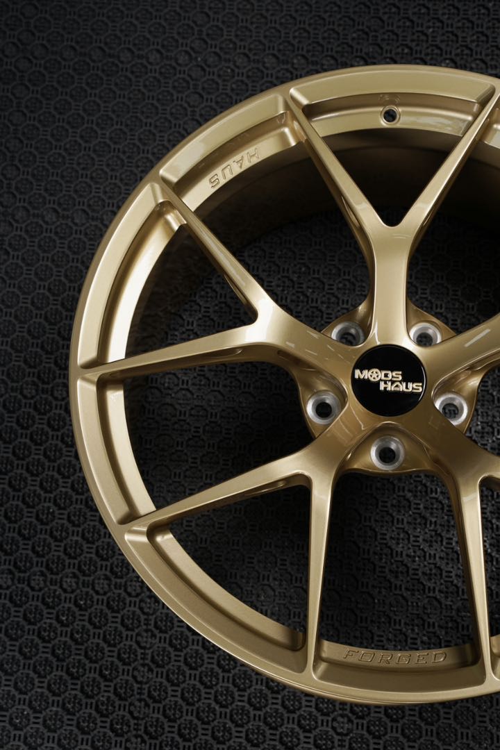 close up shot of light gold forged one piece wheels for a sports car