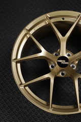 close up shot of light gold forged one piece wheels for a sports car